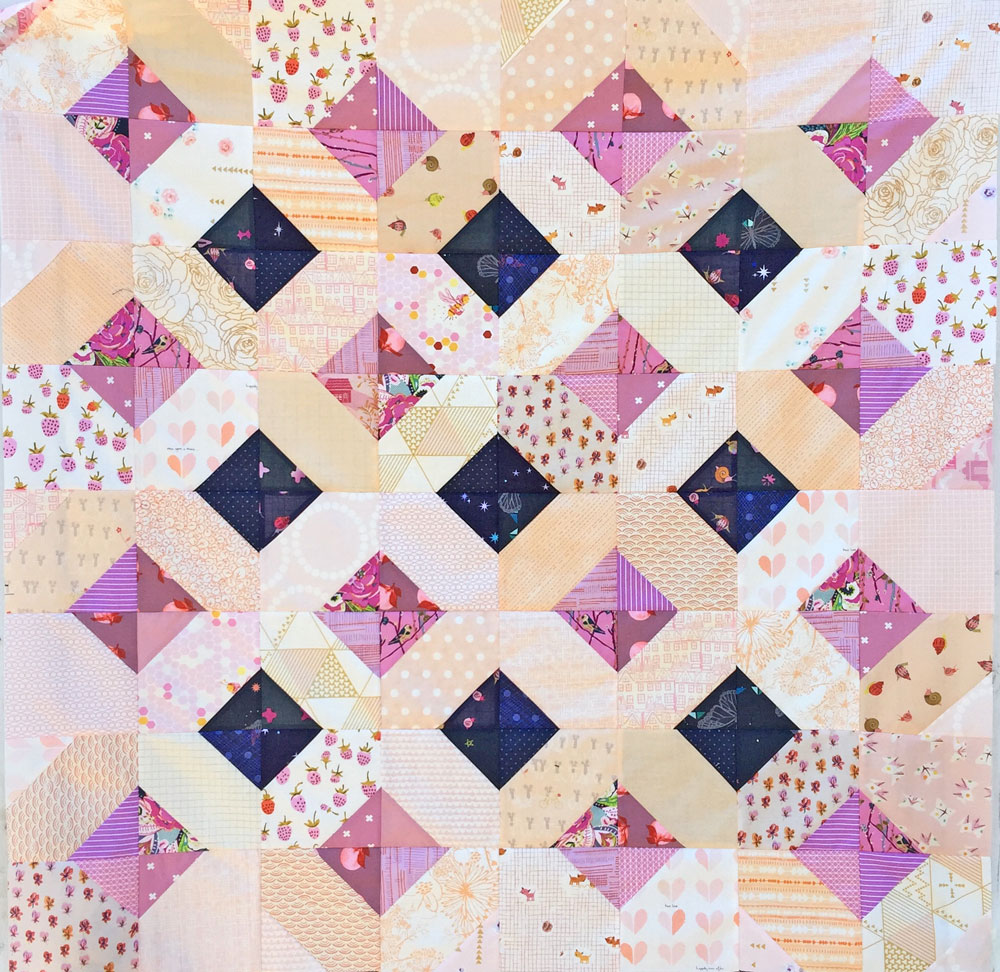 The Glitter and Glow quilt pattern can be a great way to use up scraps! Just like this sweet and scrappy purple baby quilt.