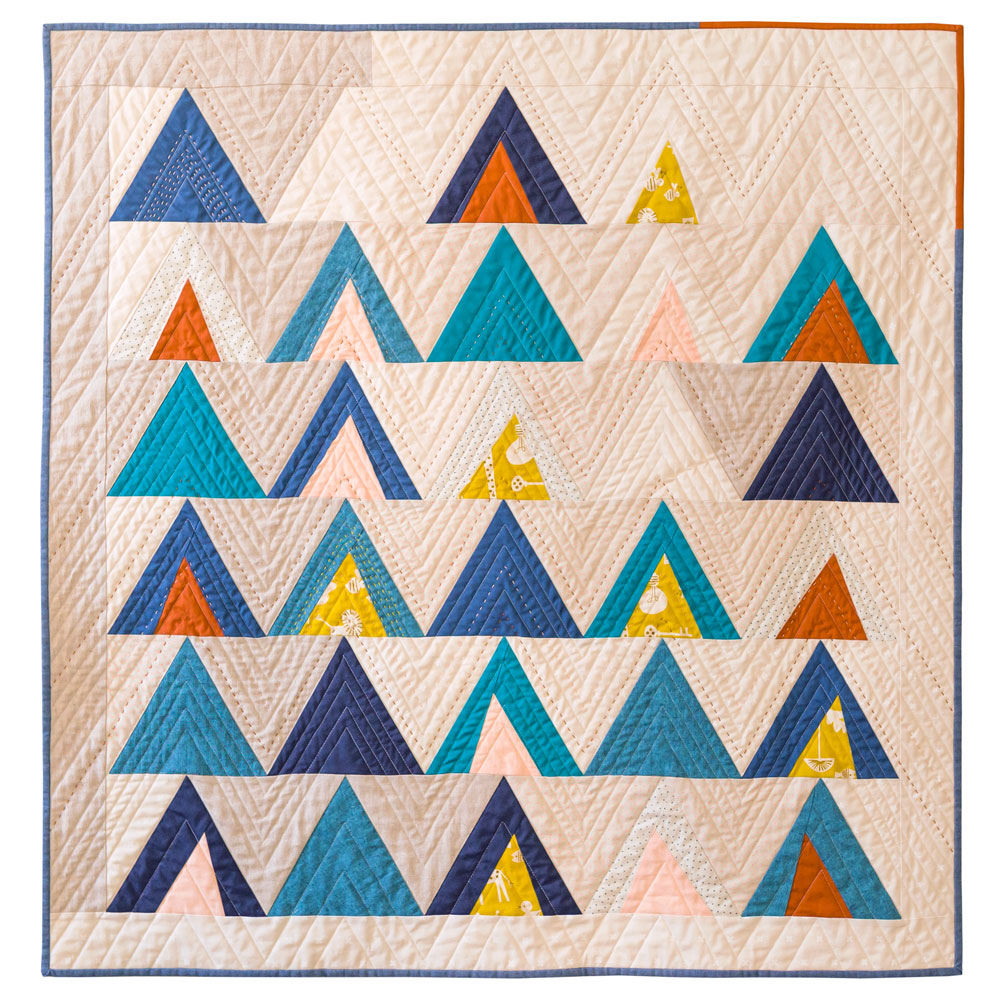 The Mod Mountains quilt pattern is fat quarter friendly and great for using fabric scraps from your stash. A video tutorial show step by step how to sew triangles. This quilt pattern includes fabric requirements for queen/full, twin, throw and baby quilt sizes. | Suzy Quilts