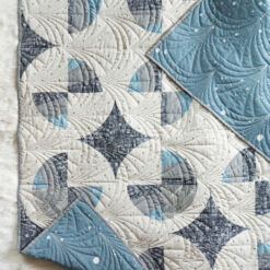 This Great Gatsby inspired Modern Fans quilt kit uses icy blues, grays and metallic silver fabric to bring elegance and pizzazz to a cozy quilt. suzyquilts.com #quiltpattern #quilt #modernquiltpattern