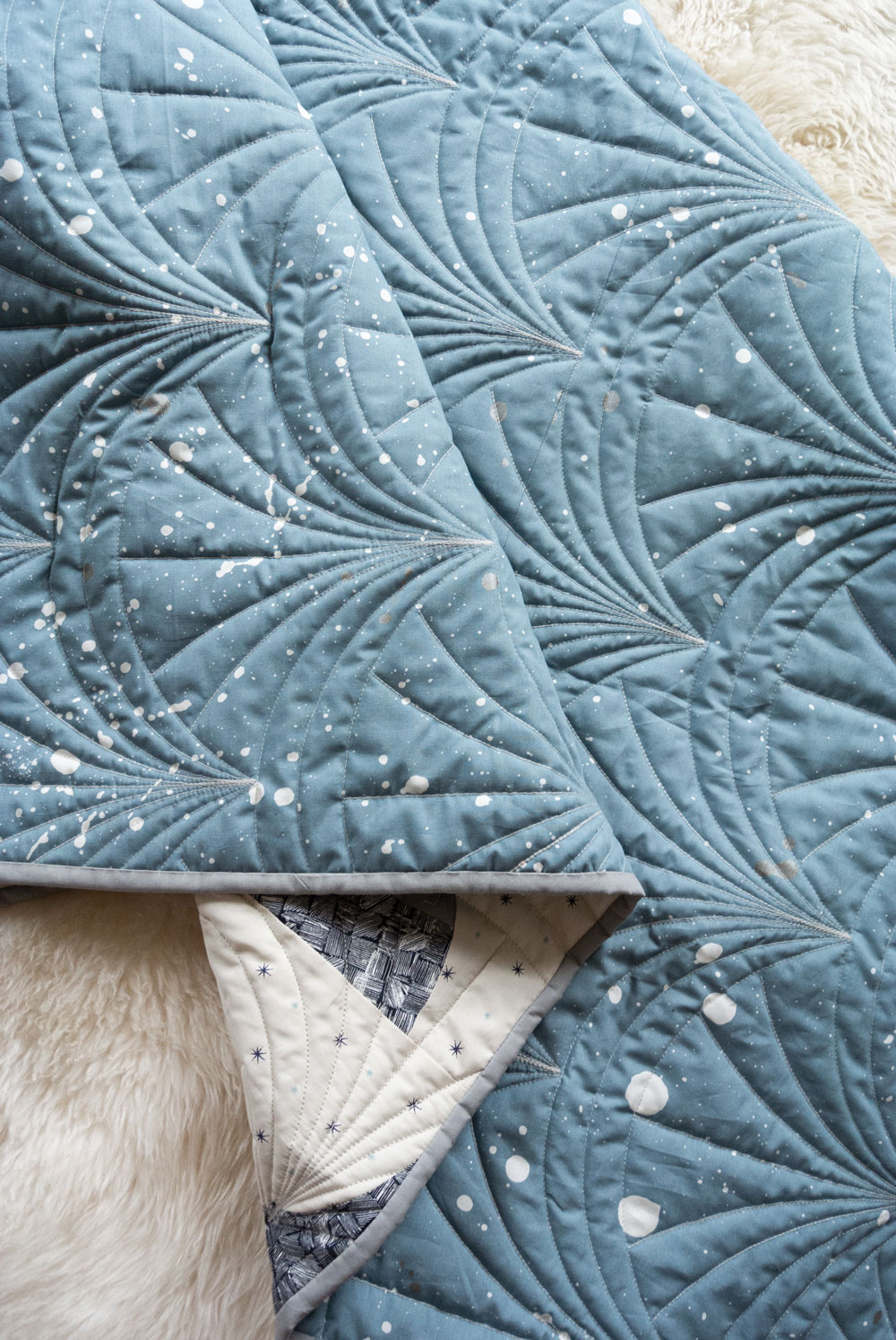 This Great Gatsby inspired Modern Fans quilt kit uses icy blues, grays and metallic silver fabric to bring elegance and pizzazz to a cozy quilt. suzyquilts.com #quiltpattern #quilt #modernquiltpattern