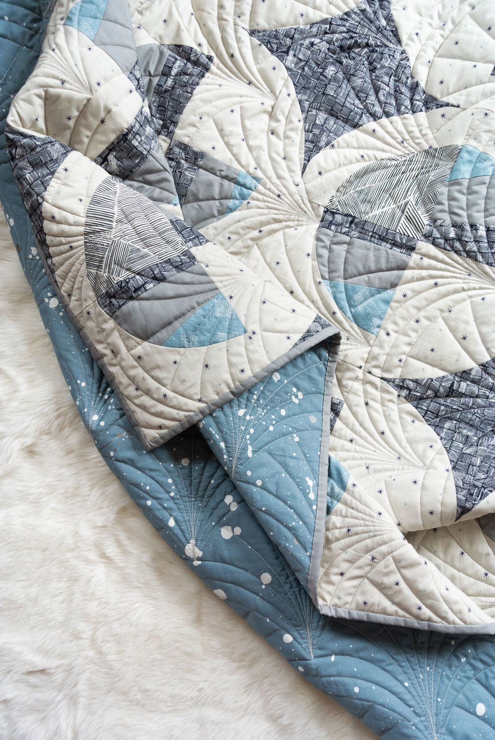 This Great Gatsby inspired Modern Fans quilt kit uses icy blues, grays and metallic silver fabric to bring elegance and pizzazz to a cozy quilt. suzyquilts.com #quiltpattern #quilt #modernquilt