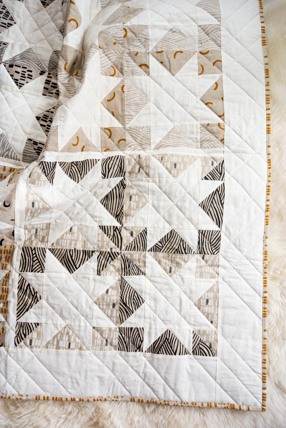 Make a sophisticated, neutral quilt using the Stars Hollow quilt pattern. This is a classic quilt pattern, but with a modern twist. The design plays on negative space to create traditional sawtooth star quilt blocks. suzyquilts.com #linen #quilting