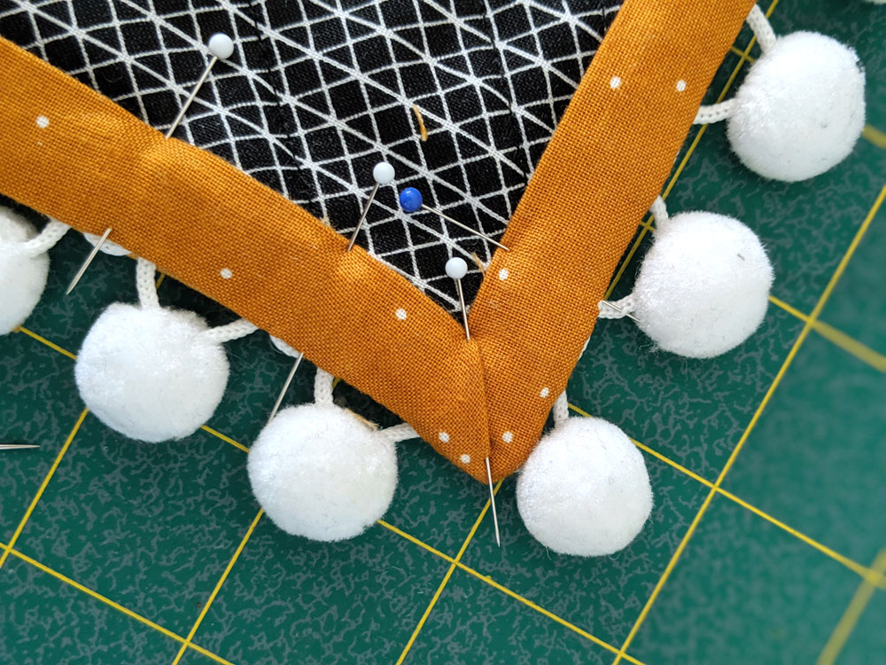 This DIY tutorial will show you step by step how to sew pom pom trim to a quilt. Make your next quilt extra special with this easy sewing tutorial | suzyquilts.com #quiltingtutorial #sewpompomtrim