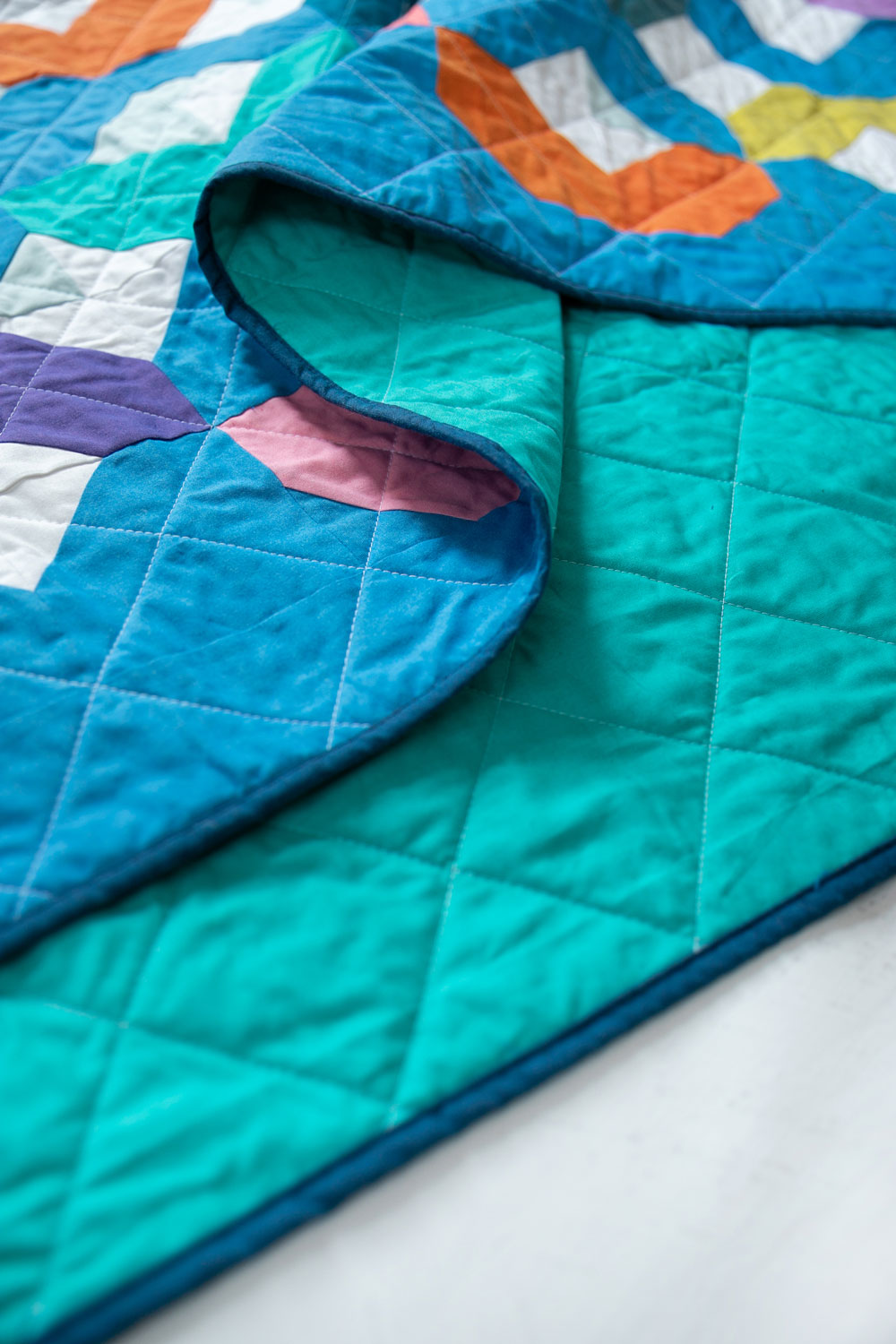 Make a Rainbow Quilt using this simple alteration to the Glitter & Glow quilt pattern. This is fat quarter friendly and great for newbie quilters and beginners. suzyquilts.com #rainbowquilt #shotcotton
