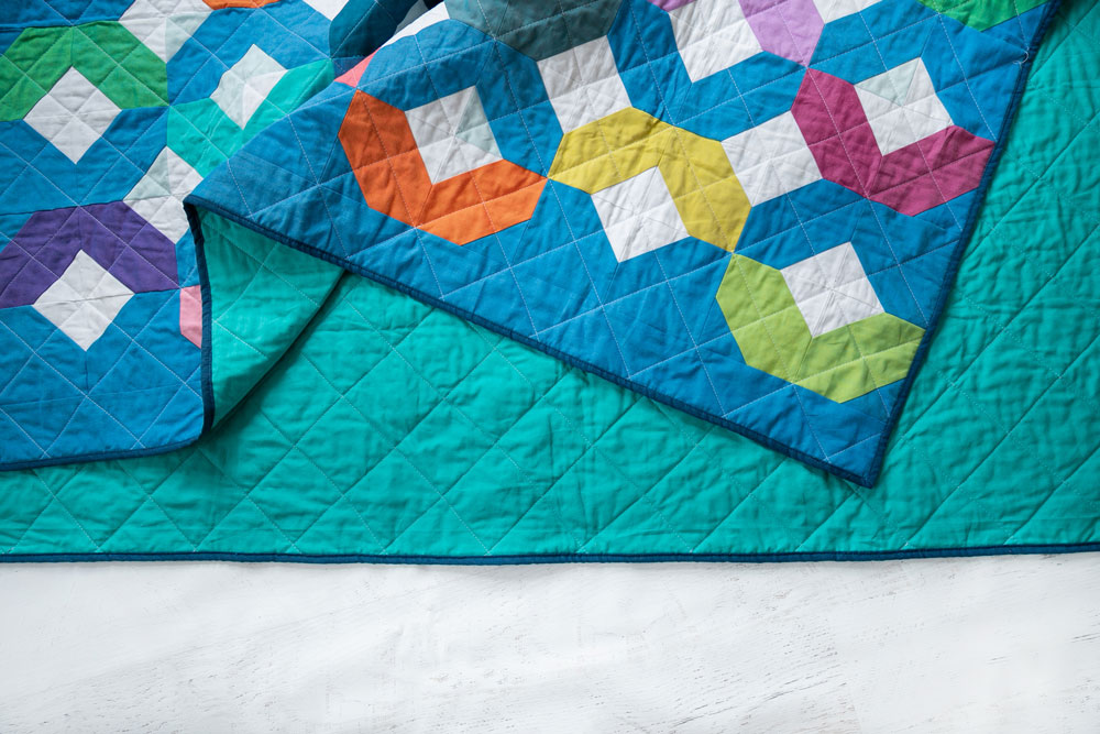 Make a Rainbow Quilt using this simple alteration to the Glitter & Glow quilt pattern. This is fat quarter friendly and great for newbie quilters and beginners. suzyquilts.com #babyquilt #rainbowbabyquilt