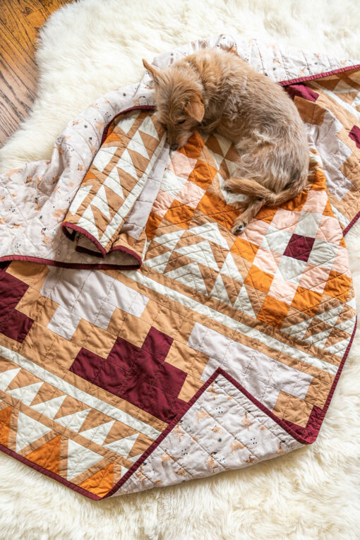 Be inspired by colors of the desert and make your own Mayan Mosaic quilt. With warm solid fabrics, this quilt pattern looks modern and timeless. With an Aztec design, this quilt kit creates a beautiful quilt! suzyquilts.com #quiltkit #dogquilt #quiltpattern
