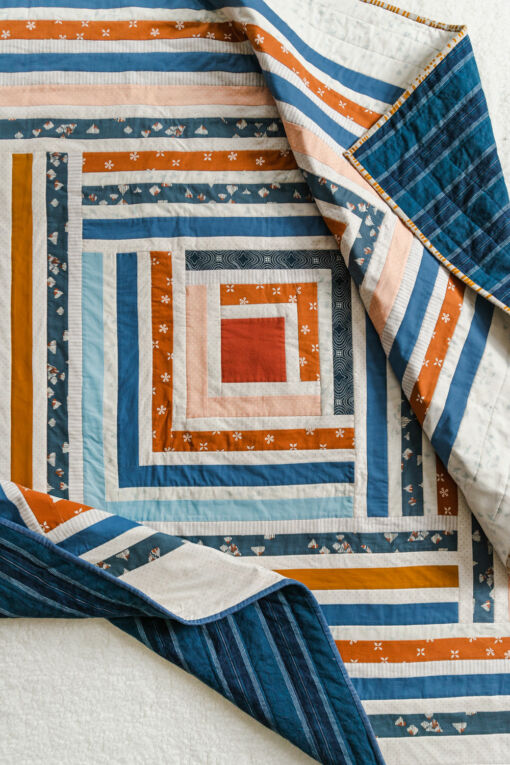 Sew a scrappy modern quilt with the Campfire quilt pattern. Based on the traditional log cabin quilt pattern, use long strips of fabric and scraps! suzyquilts.com #logcabinquilt #modernquilt