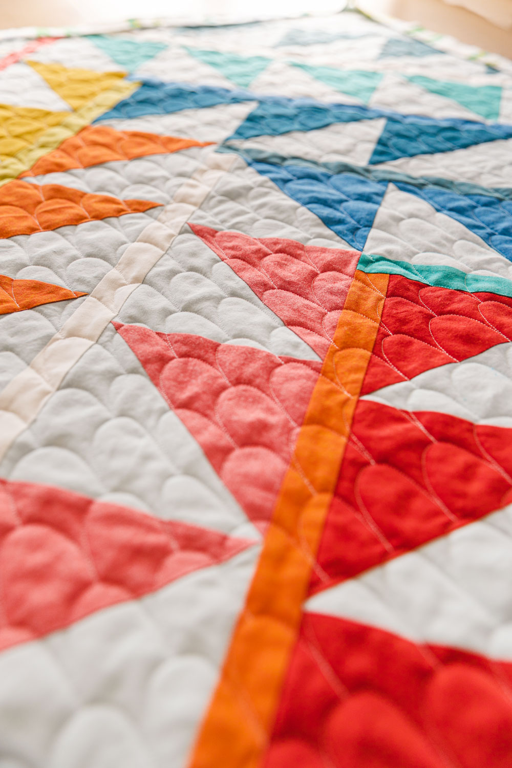 This simple free motion quilting tutorial will show you how easy and FUN free motion quilting can be! With just a few tools, and some practice, you will be a FMQ rockstar and able to quilt this adorable scallops motif just like me! suzyquilts.com #fmq #quilting