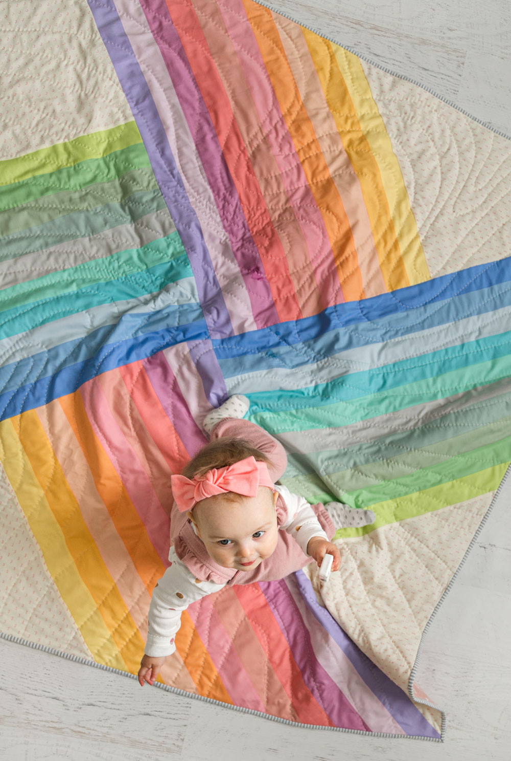6 Steps for Mindful Making: A baby girl crawling on an Adventureland quilt made in pastel rainbow colors. #quilting suzyquilts.com