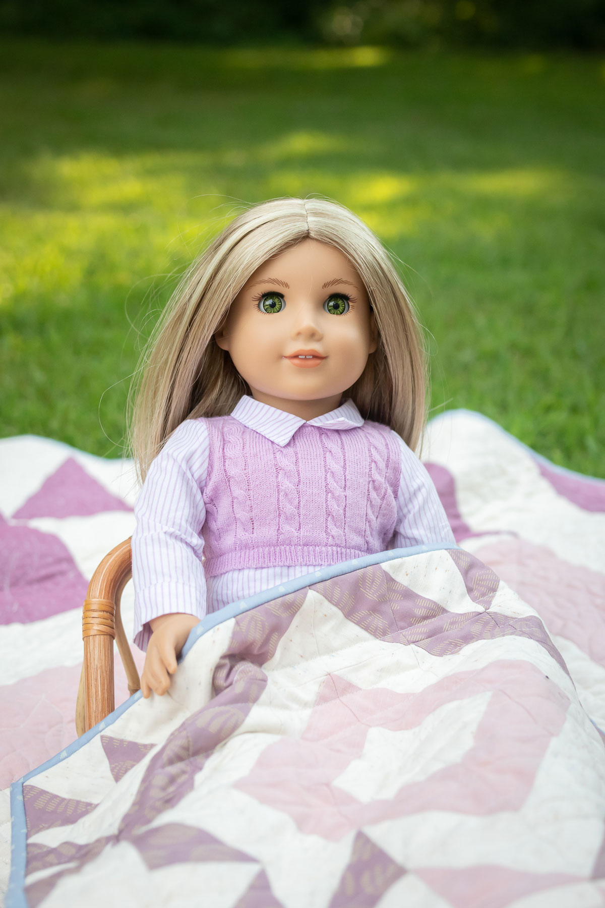 A doll sitting in a doll bed with a pink and purple Triangle Jitters quilt. #Quilting #SewingDIY suzyquilts.com A doll sitting in a doll bed with a pink and purple Triangle Jitters quilt. #Quilting #SewingDIY suzyquilts.com