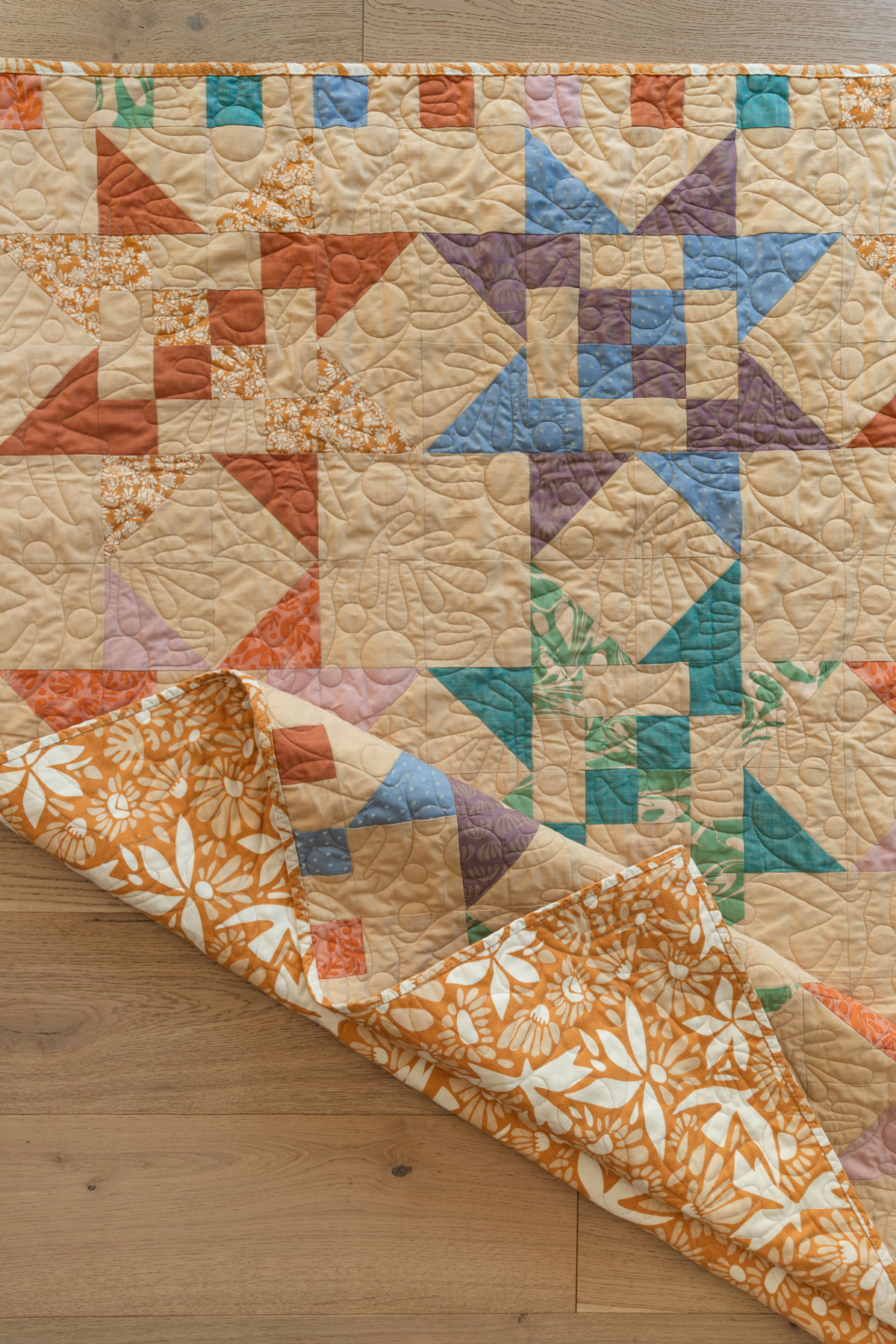 A Fat Quarter Stars quilt pattern by Suzy Quilts with a neutral background and orange, green, and purple stars. #Quilting #SewingDIY suzyquilts.com A Fat Quarter Stars quilt pattern by Suzy Quilts with a neutral background and orange, green, and purple stars. #Quilting #SewingDIY suzyquilts.com