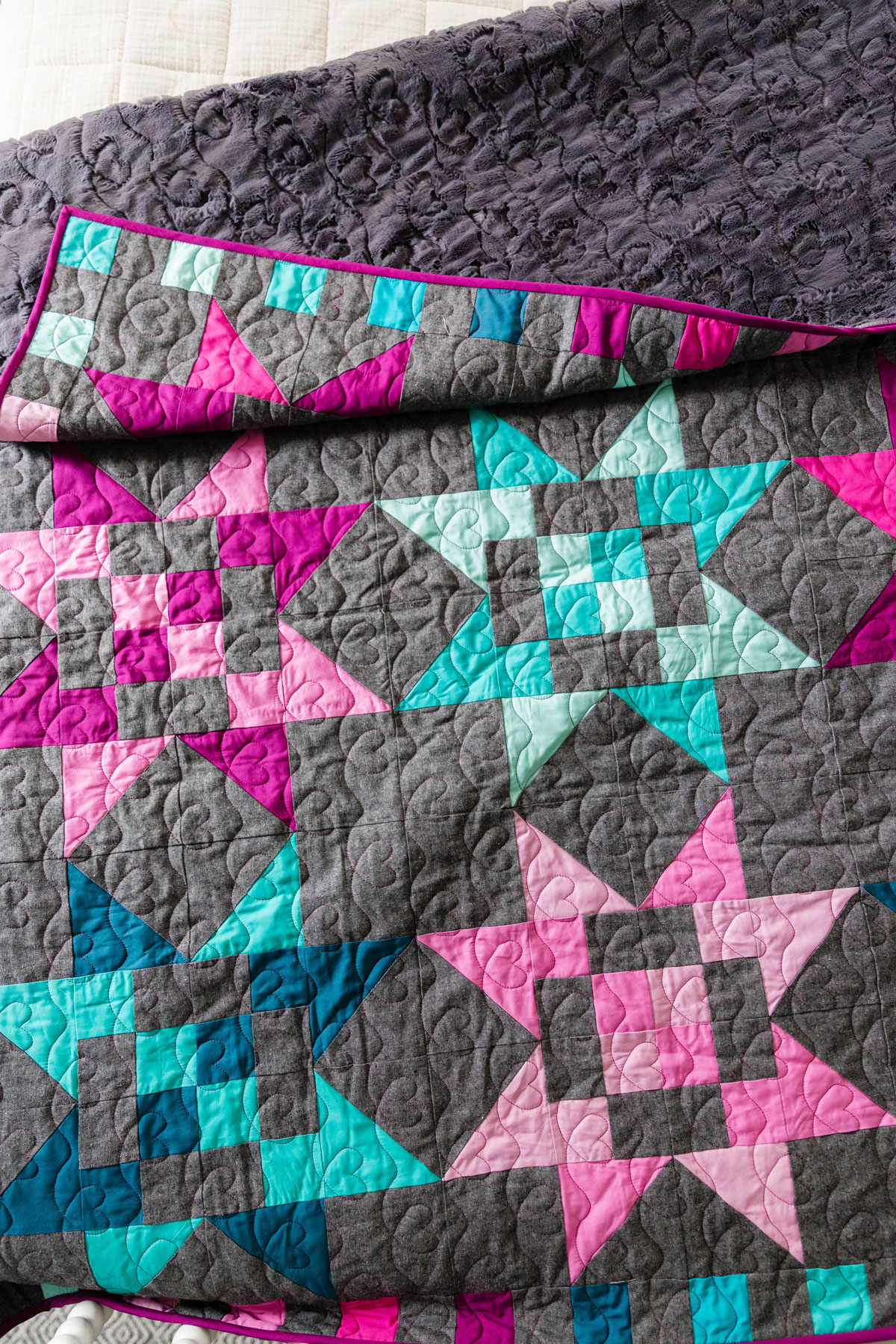 A Fat Quarter Stars quilt made using teal and magenta stars with a dark background. #Quilting #SewingDIY suzyquilts.com A Fat Quarter Stars quilt made using teal and magenta stars with a dark background. #Quilting #SewingDIY suzyquilts.com