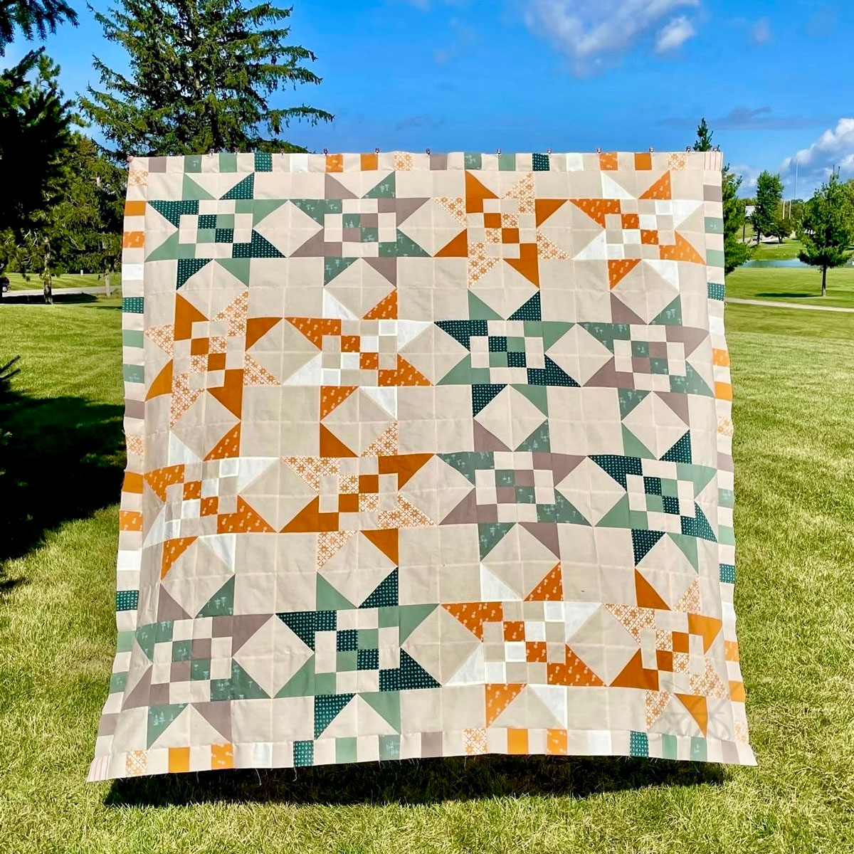 A Fat Quarter Stars quilt with a neutral background and green and orange stars. #Quilting #SewingDIY suzyquilts.com A Fat Quarter Stars quilt with a neutral background and green and orange stars. #Quilting #SewingDIY suzyquilts.com